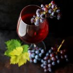 Guida Essenziale ai Vini d'Italia calice di vino rosso con grappoli di uva