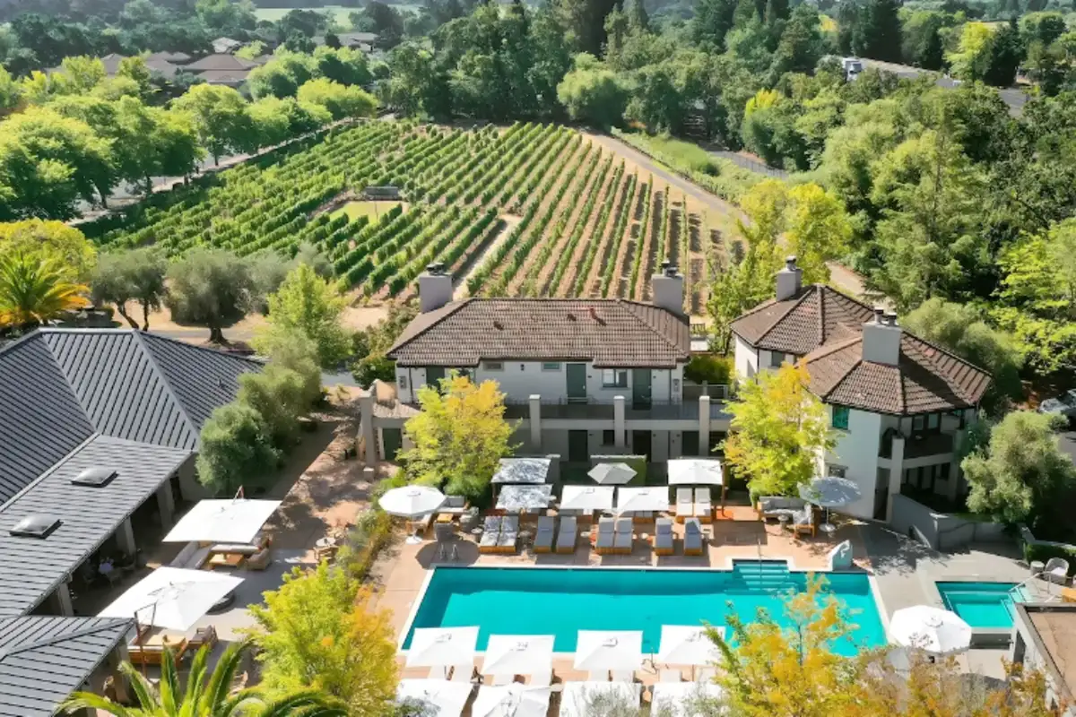 Aerial view of The Estate Yountville: swimming pool, guest buildings and vineyard rows behind the trees