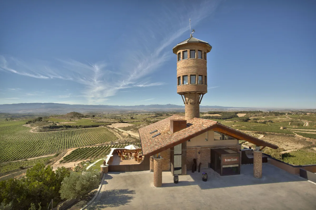 Stone tower and winery building surrounded by vineyards at Hotel Eguren Ugarte near Laguardia