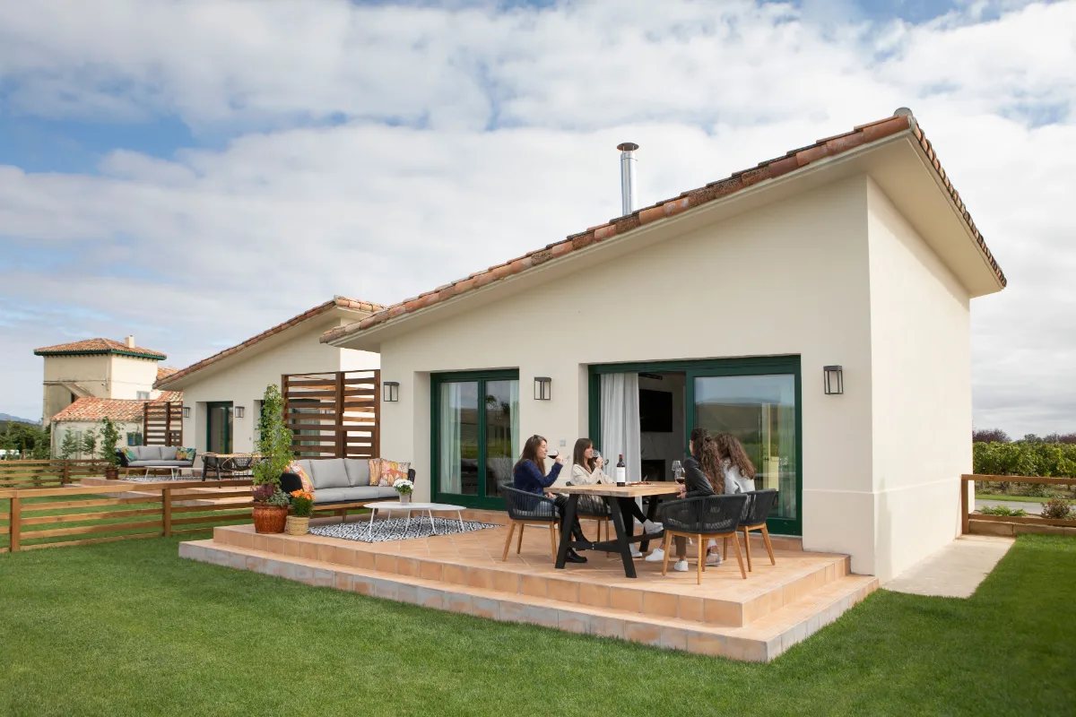 Single-storey villa with a wooden terrace and two guests seated at Villas Finca La Emperatriz in Banos de Rioja