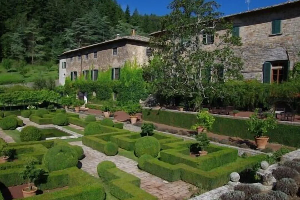 Clipped box-hedge parterre garden in front of the stone abbey buildings at Badia a Coltibuono, Gaiole in Chianti