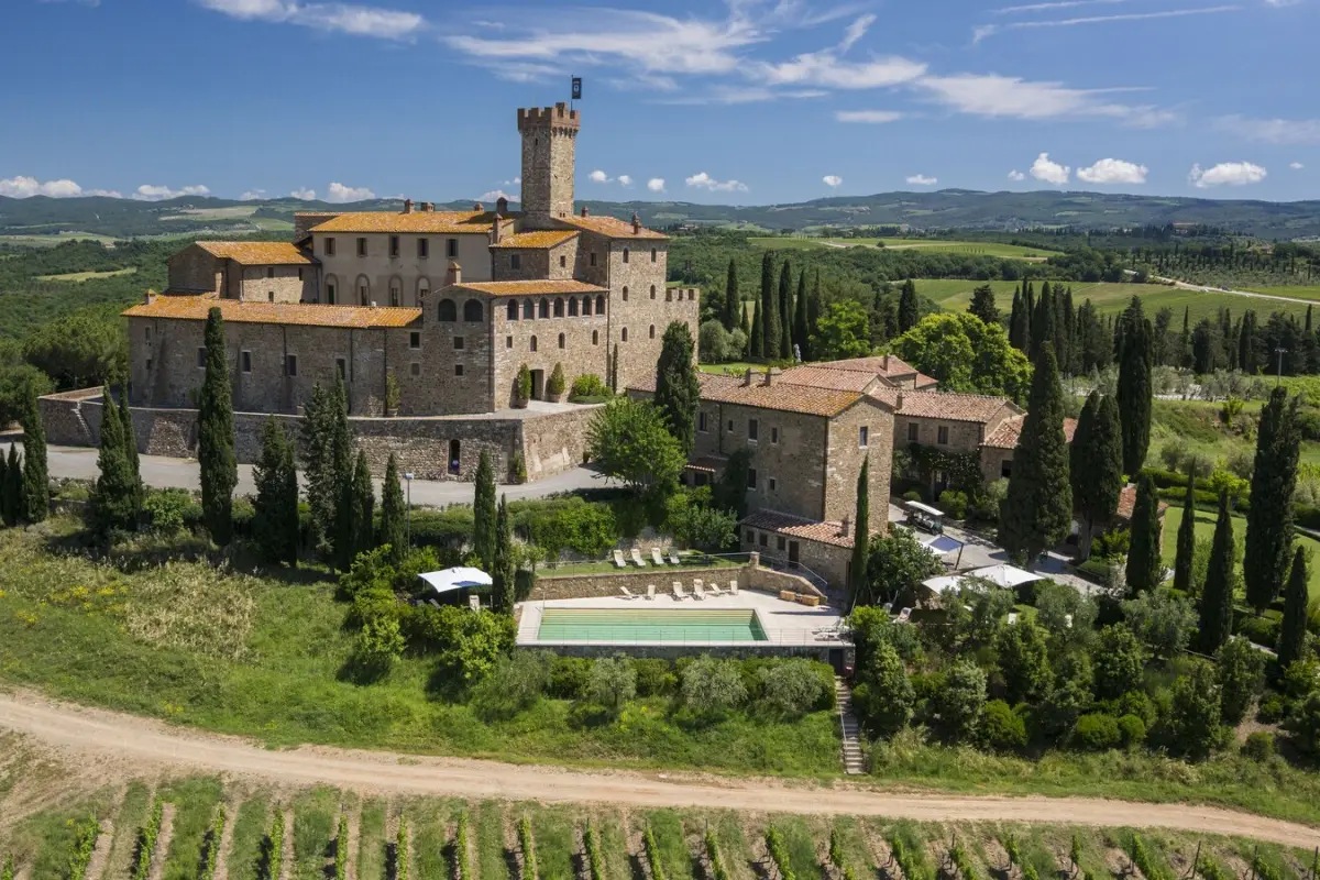 The hilltop castle, cypresses and gardens at Castello Banfi, the grandest of the Montalcino estates with rooms, seen across the valley at Poggio alle Mura