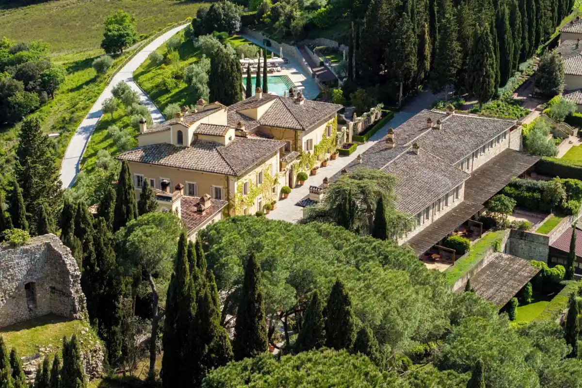 Aerial view of the stone hamlet, pool and lawns of Castiglion del Bosco enclosed by woodland northwest of Montalcino