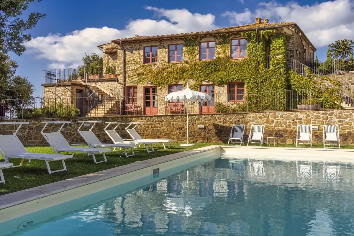 Swimming pool and sun loungers beside the stone farmhouse at Le Ragnaie, a few minutes from the fortress of Montalcino