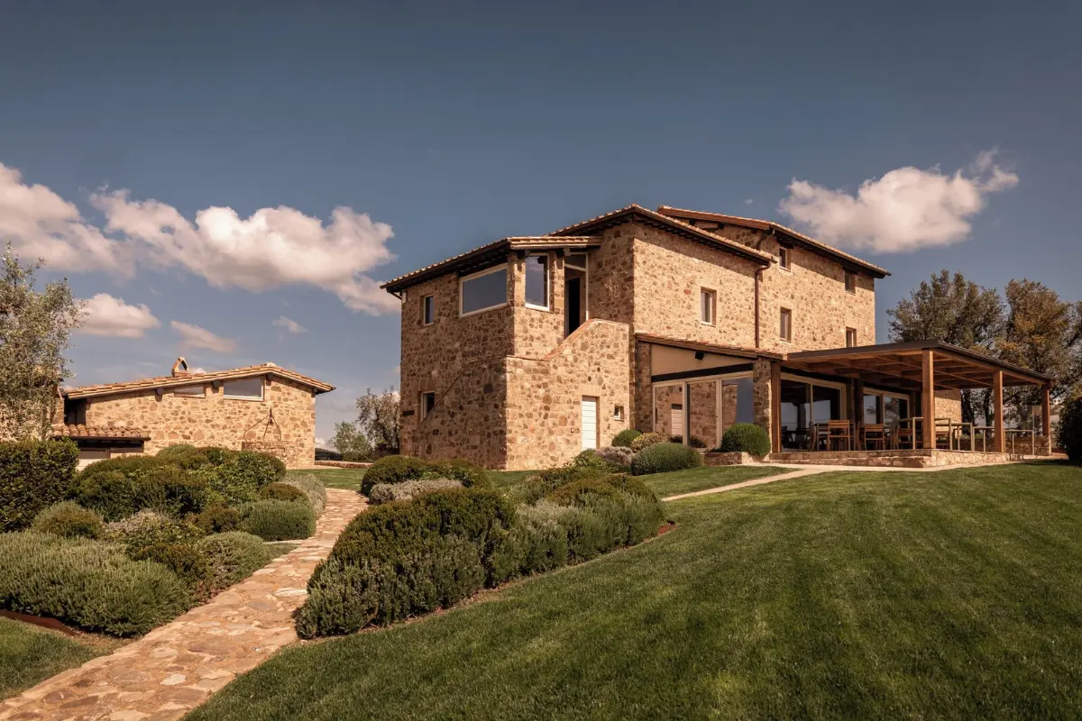Stone farmhouse with a square tower, clipped hedges and lawn at Mastrojanni Relais in Castelnuovo dell'Abate