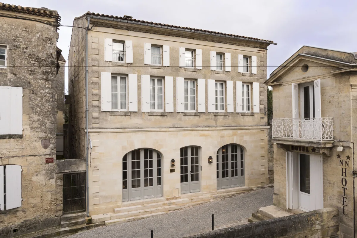 The tall limestone facade of Auberge de la Commanderie on a corner inside the walls of Saint-Émilion