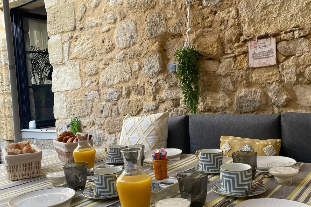 A breakfast table laid in front of the bare limestone wall of a room at La Maison du Clocher in Saint-Émilion
