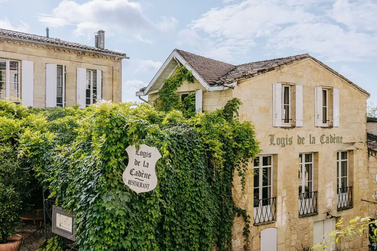 The ivy-covered stone facade of Logis de la Cadène on its square in the center of Saint-Émilion