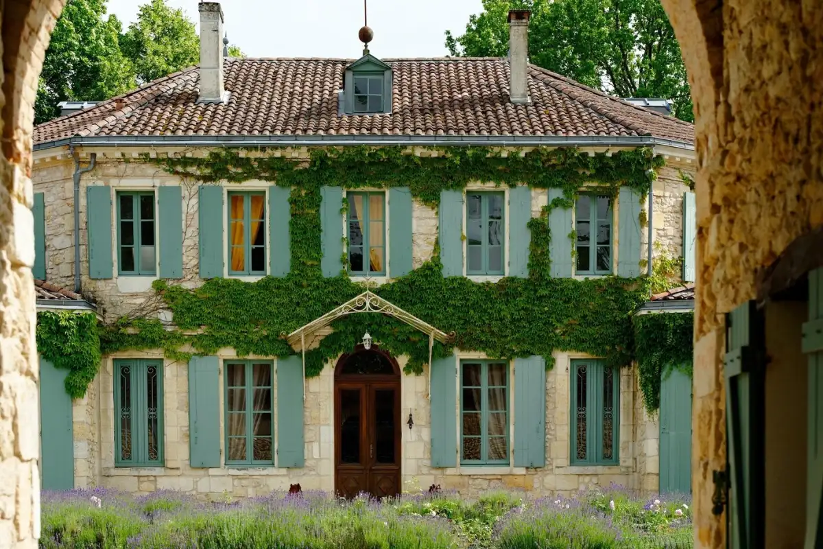 The ivy-covered stone façade of Château de l'Isle at Castelnau-de-Médoc, with pale blue-green shutters and lavender along the front
