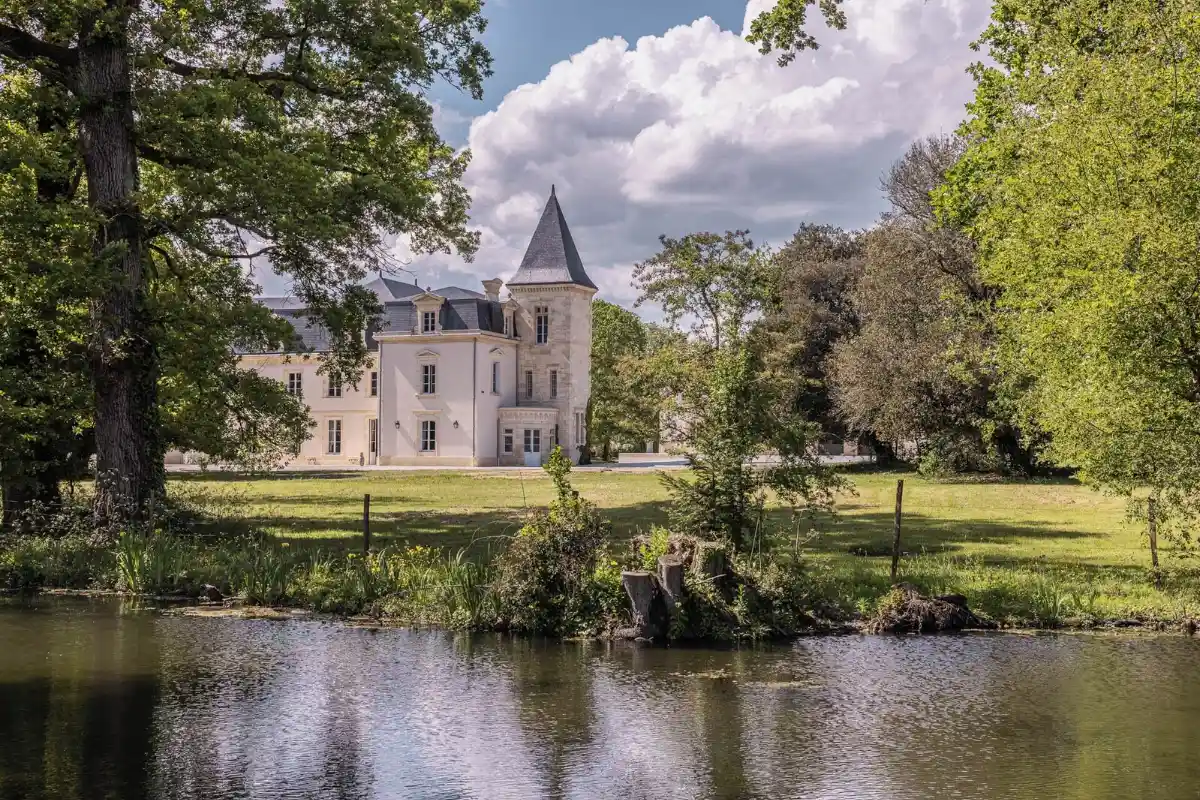 Château Sénéjac at Le Pian-Médoc seen across its own pond, the conical-roofed tower rising behind old oaks