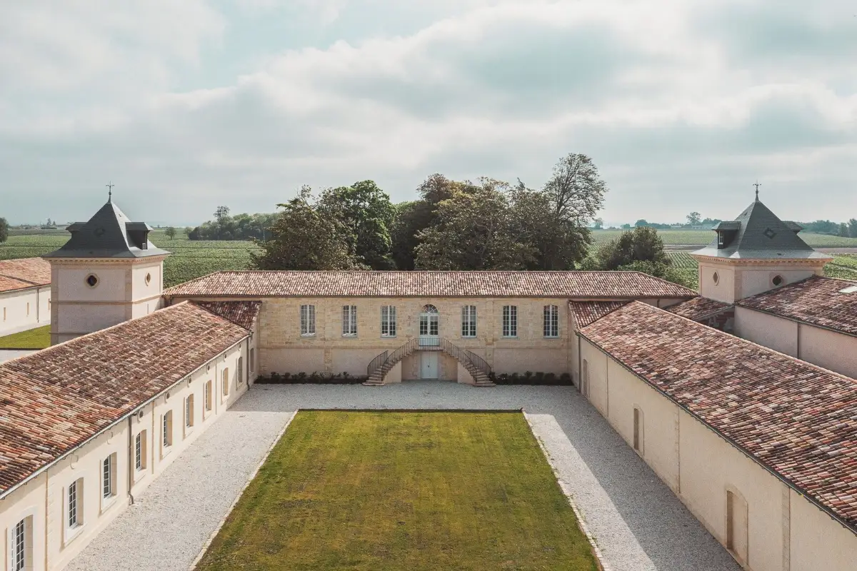Château Laffitte Carcasset from the air, its walled courtyard flanked by two pepper-pot towers with vineyards beyond