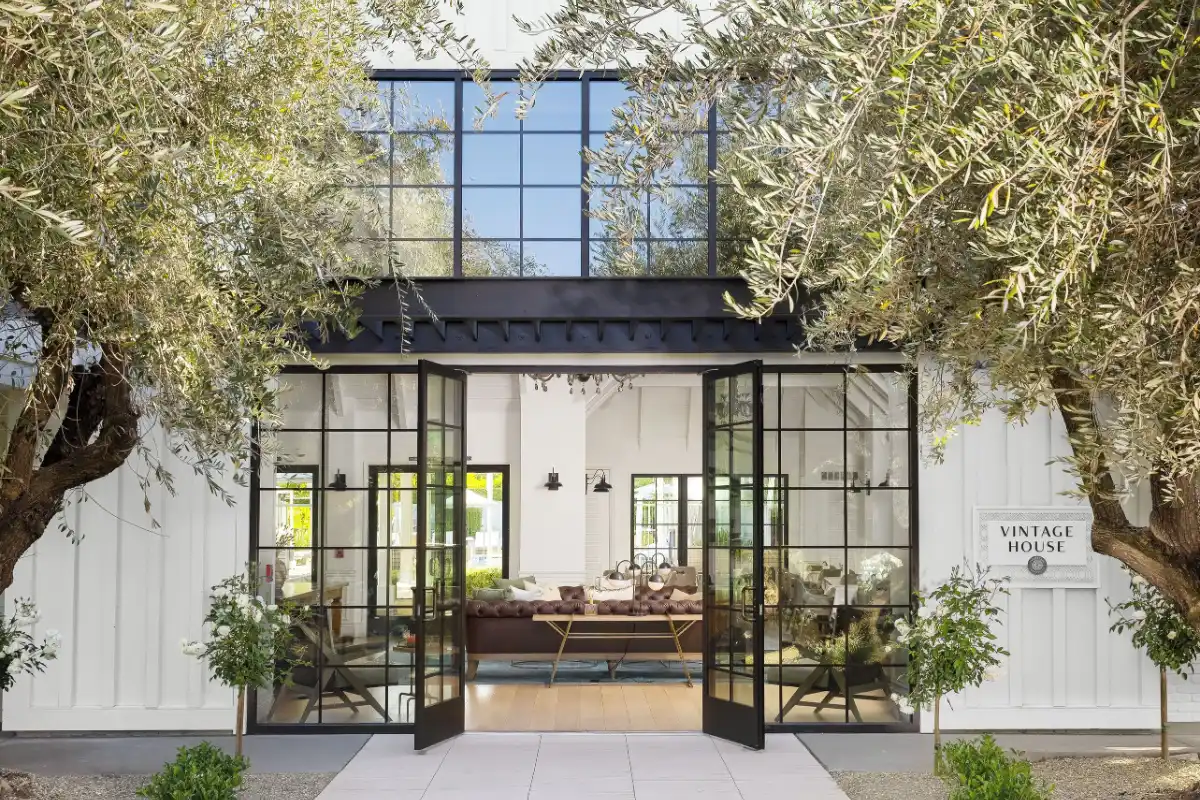 Tall black-framed glass doors and olive trees outside the Vintage House building at The Estate Yountville