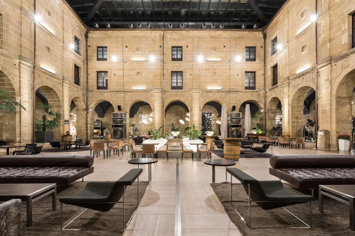 Glass-roofed stone cloister with seating and plants at Eurostars Los Agustinos in Haro