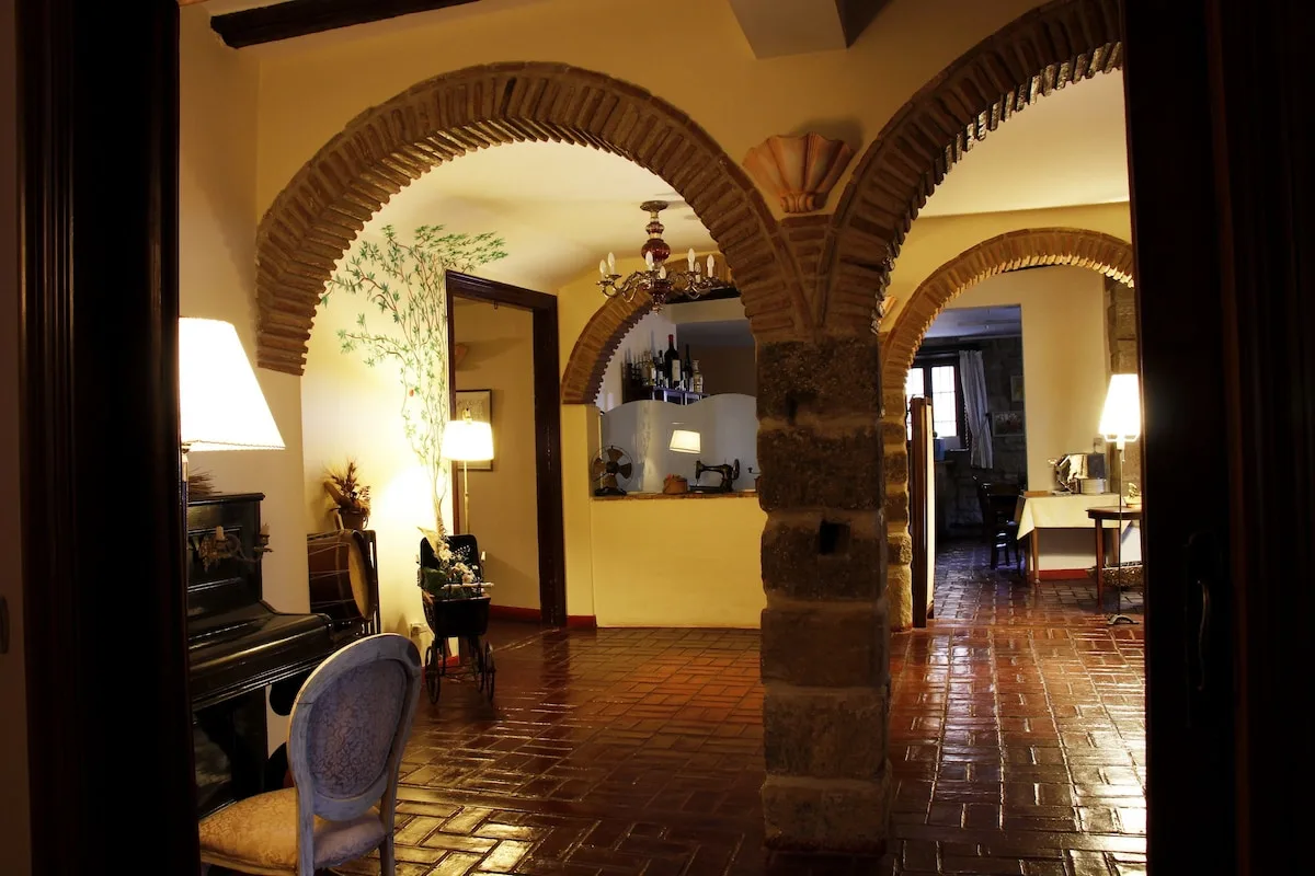 Stone-arched salon with lamps and a piano at Hospederia Senorio de Brinas