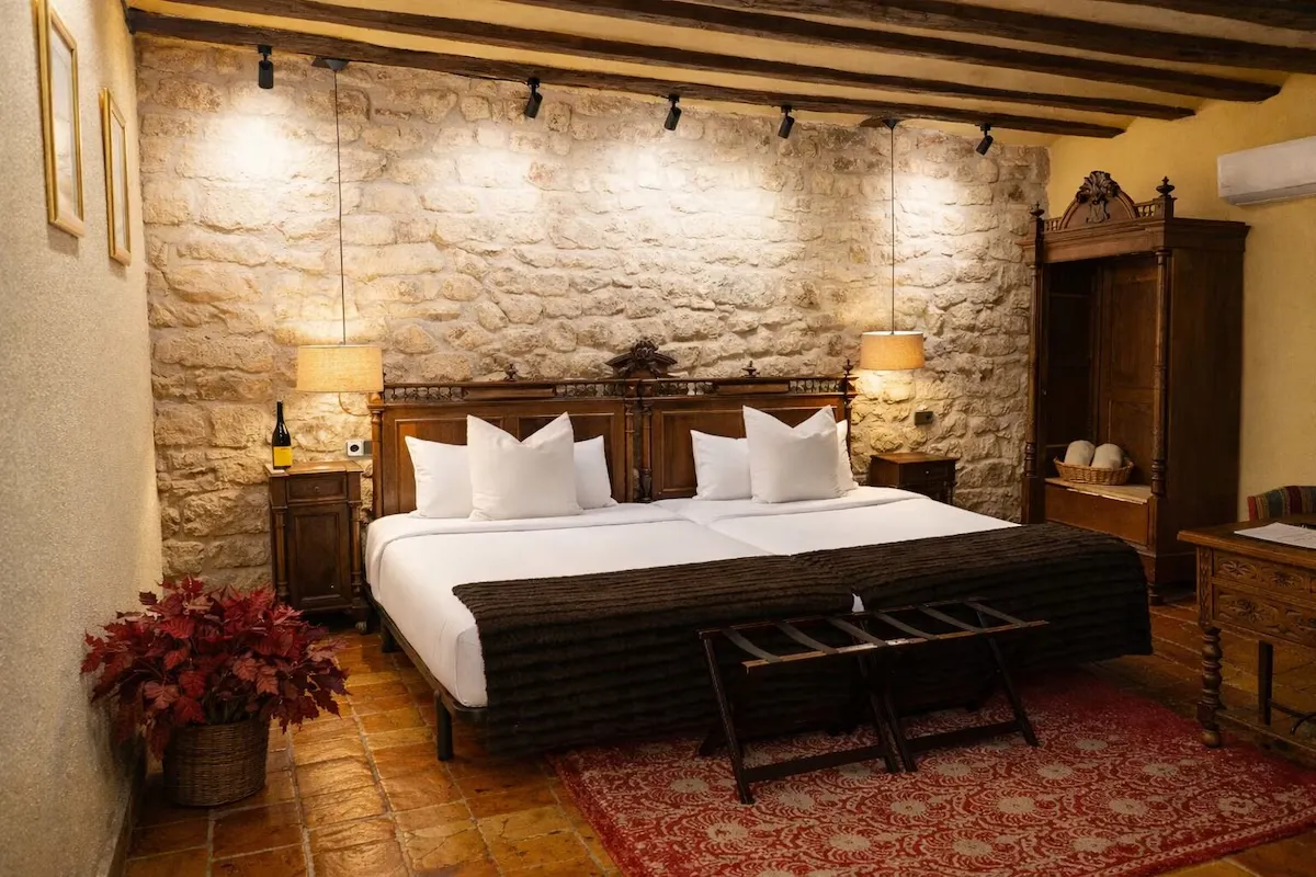 A bedroom with exposed stone walls and wooden beams at Hotel Posada Mayor de Migueloa in Laguardia