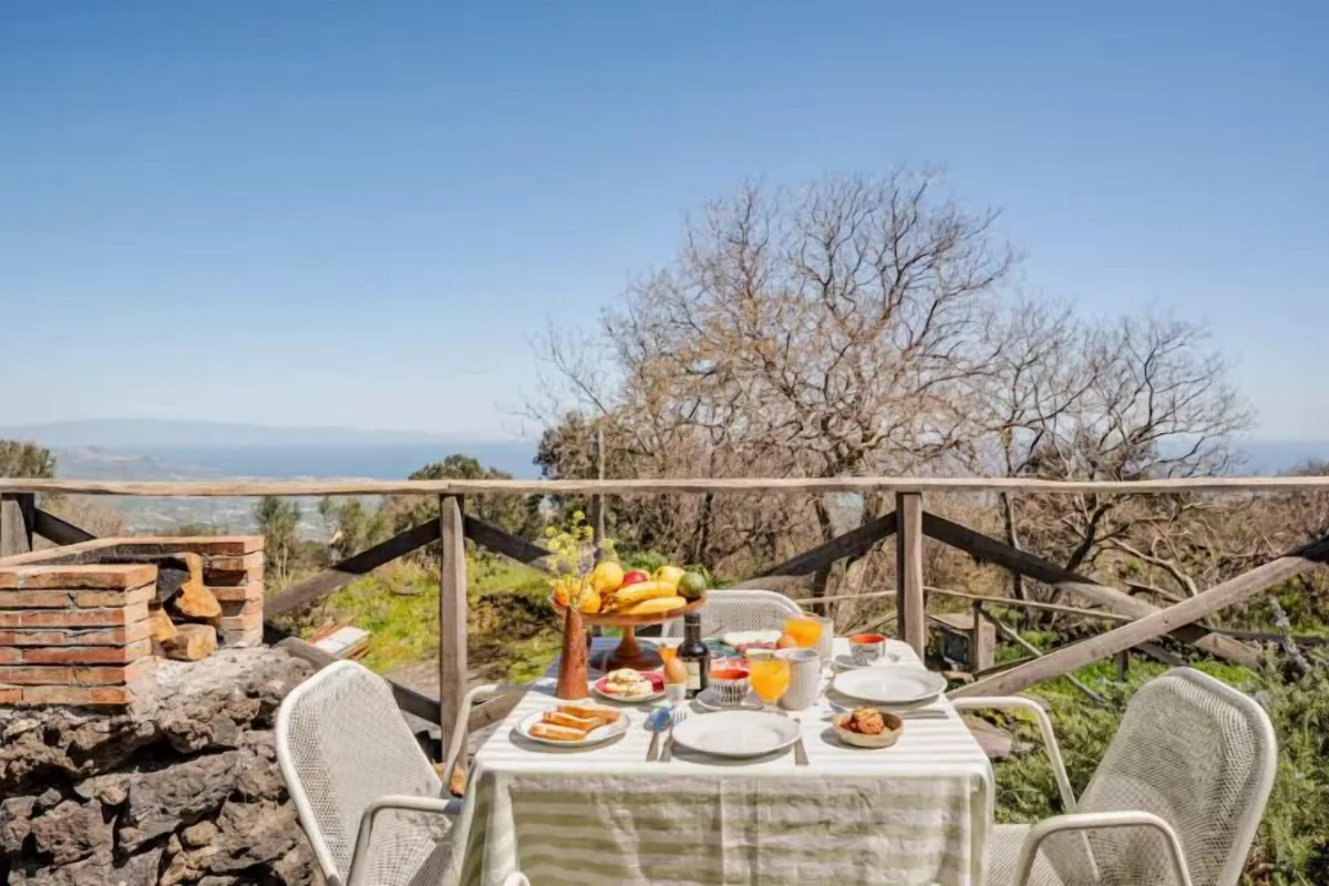 Breakfast laid out on the terrace at Etnella, with the sea visible beyond the trees