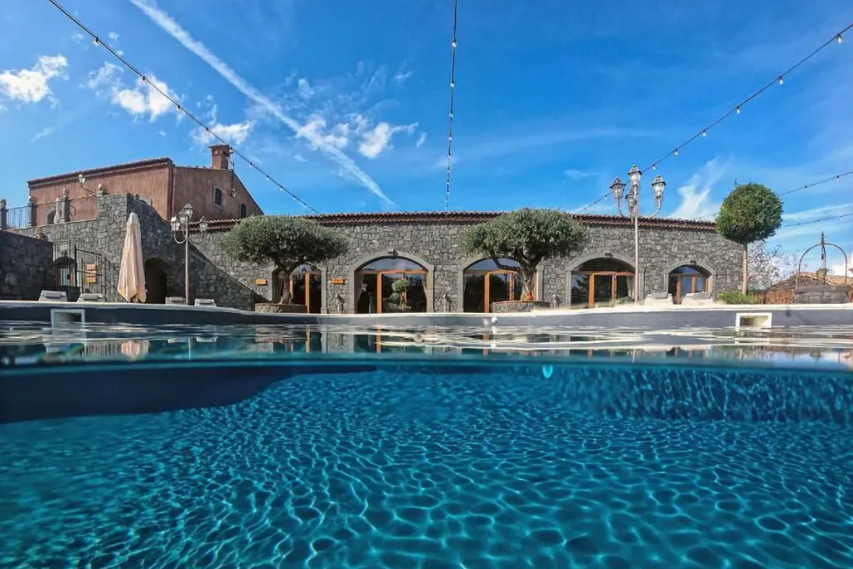 Pool and stone buildings with arched doorways at Etna Quota Mille near Randazzo