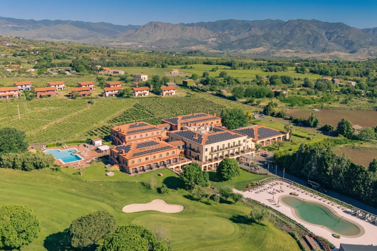 Aerial view of Picciolo Etna Golf Resort and its golf course, with Mount Etna behind, in Castiglione di Sicilia