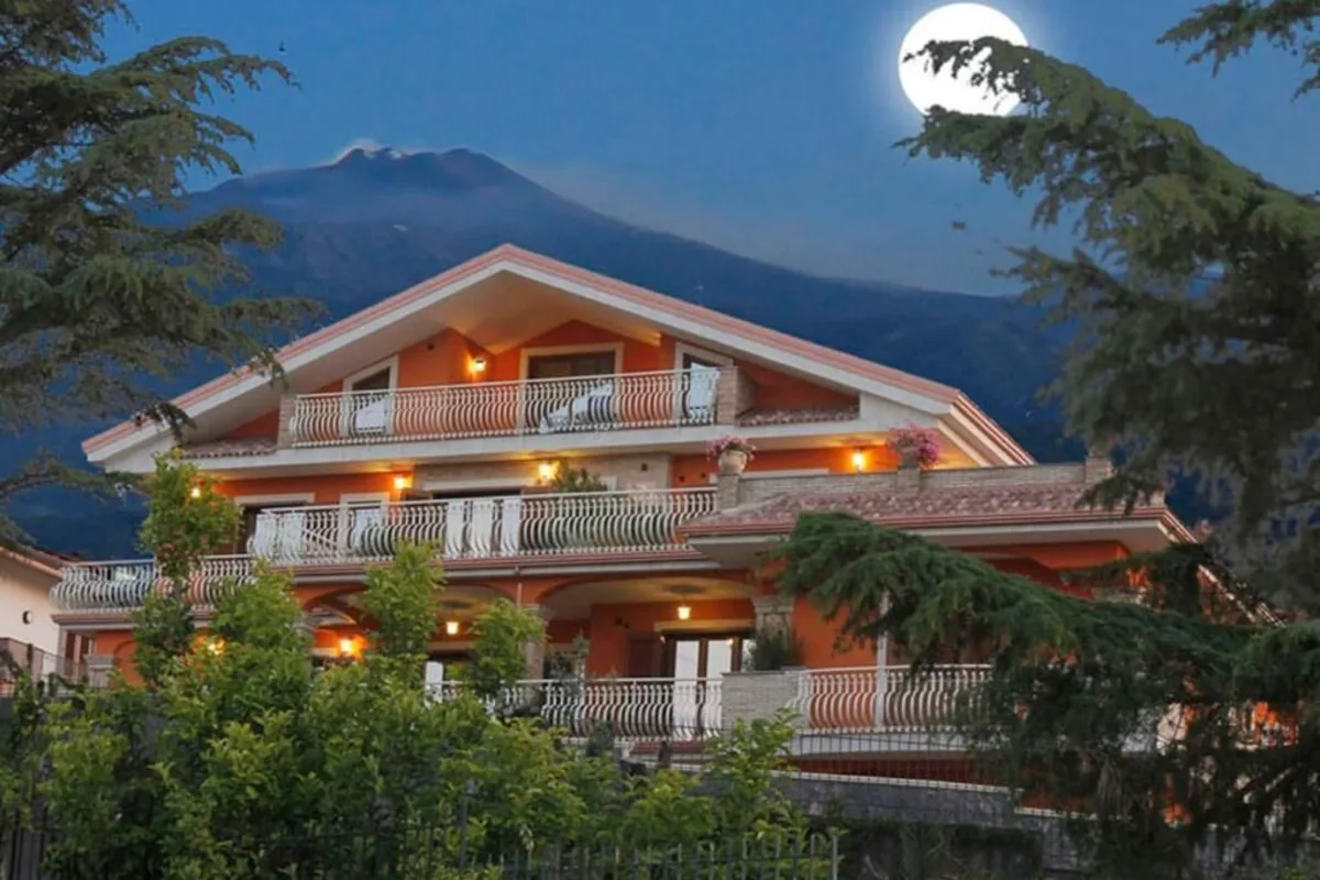 Etna Royal View, a terracotta-colored house with balconies on the green slopes above Trecastagni