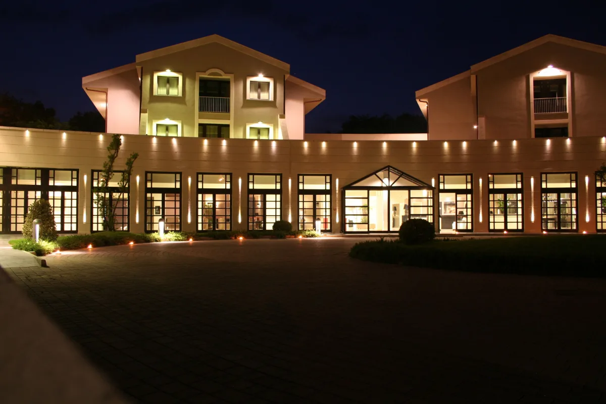Grand Hotel Villa Itria in Viagrande lit up at dusk, with its long facade and lawn