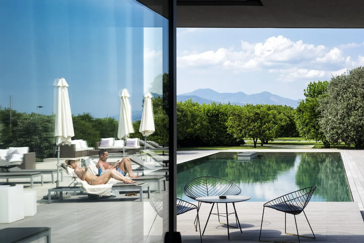 Pool and loungers beside the citrus grove at Zash Country Boutique Hotel in Riposto, with hills behind