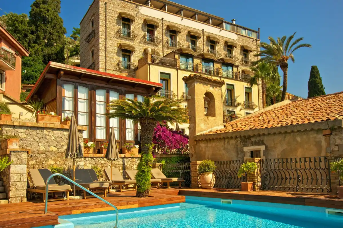 Pool and garden below the stone villa of Hotel Villa Carlotta in Taormina
