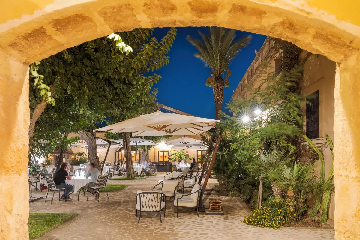 Courtyard tables under a stone arch at Baglio Oneto near Marsala, lit at dusk