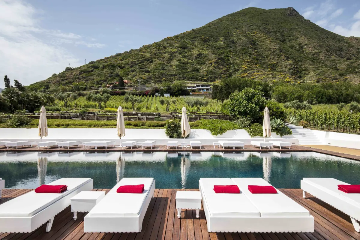 Pool and sunbeds below a green hillside at Capofaro Locanda & Malvasia on Salina