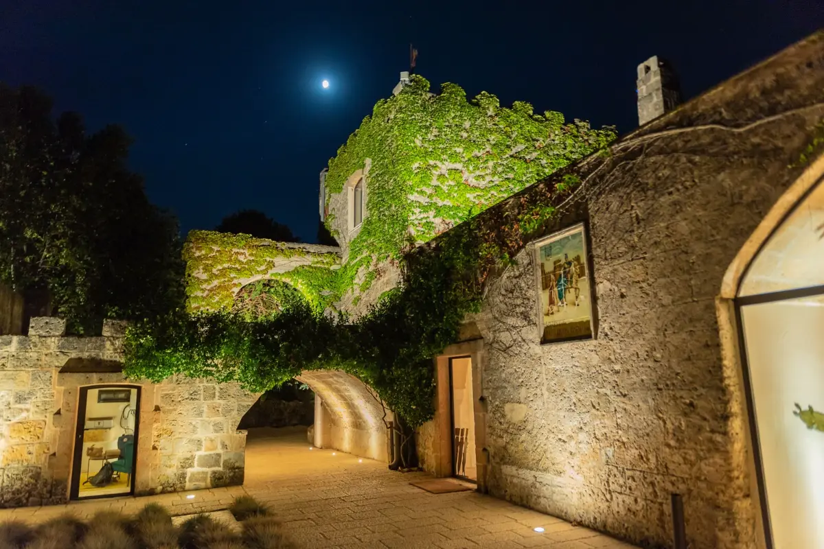 Ivy-covered stone walls and an arched passage in the courtyard of Masseria Li Reni at night