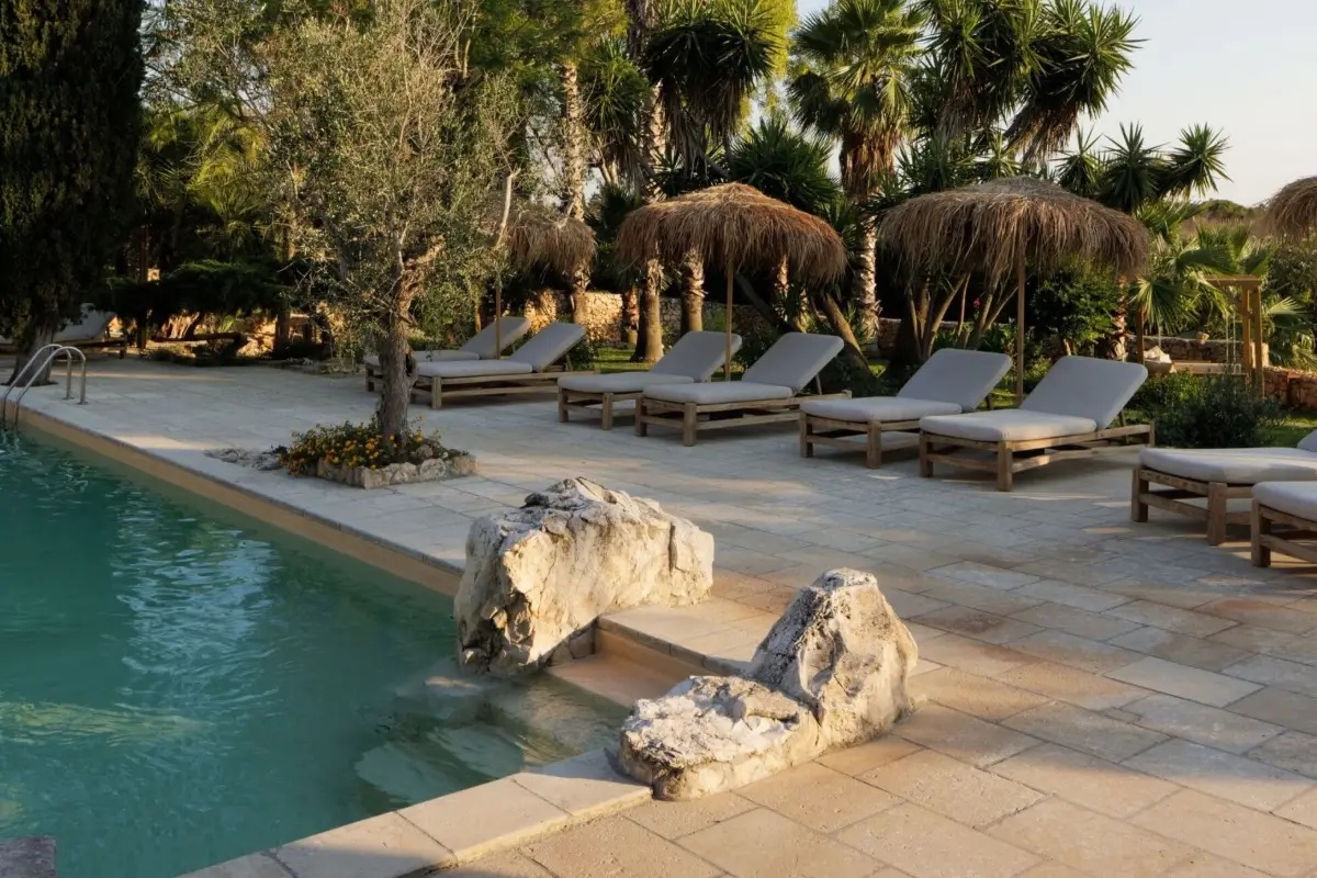Pool among olive trees and thatched parasols at Tenuta Negroamaro near Gallipoli