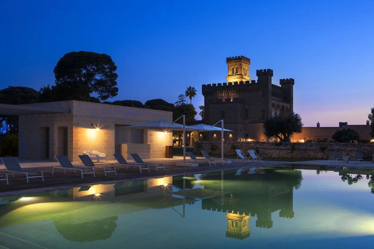 The castle tower of Vinilia Wine Resort lit at dusk above the pool