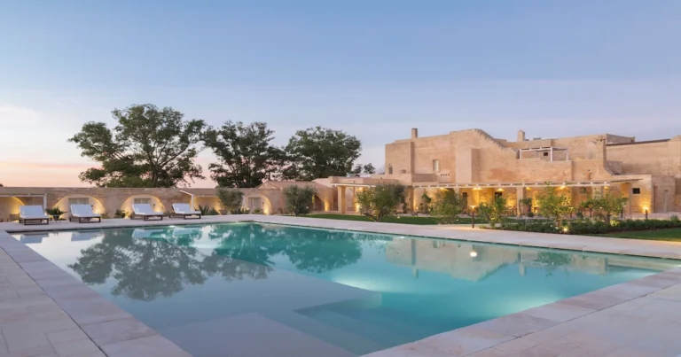 Where to stay in Salento: Masseria Donna Menga at dusk, lit stone walls above the pool near Nardò.
