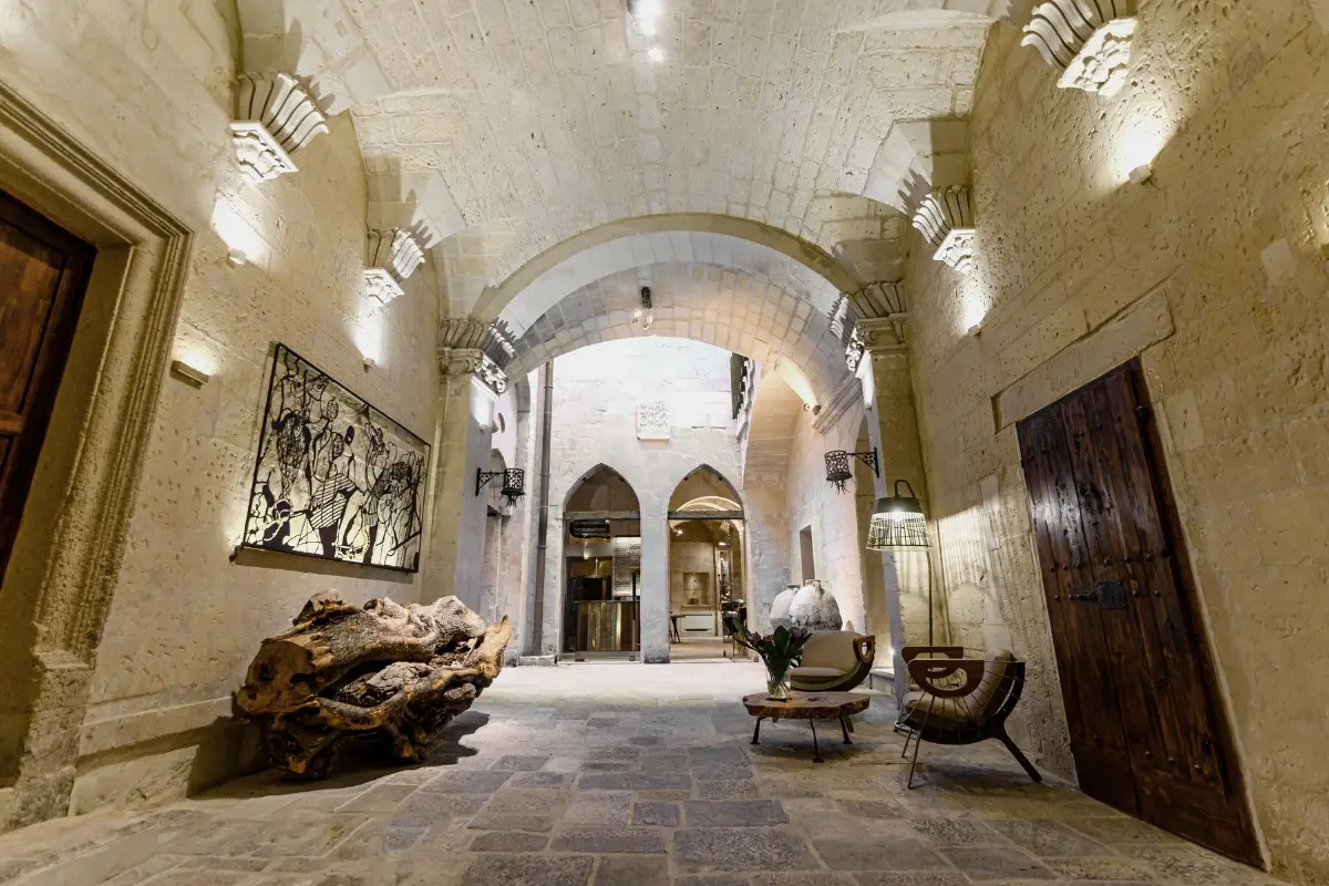 Vaulted stone hallway of Pollicastro Boutique Hotel in Lecce, with arched doorways and warm lighting
