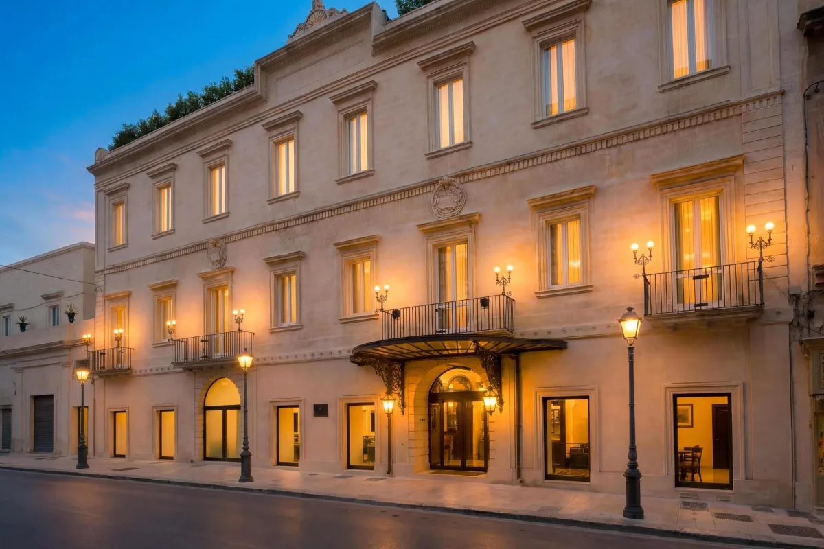 Lamp-lit facade of Tivoli Palazzo 1880 on a street in the old town of Lecce at dusk