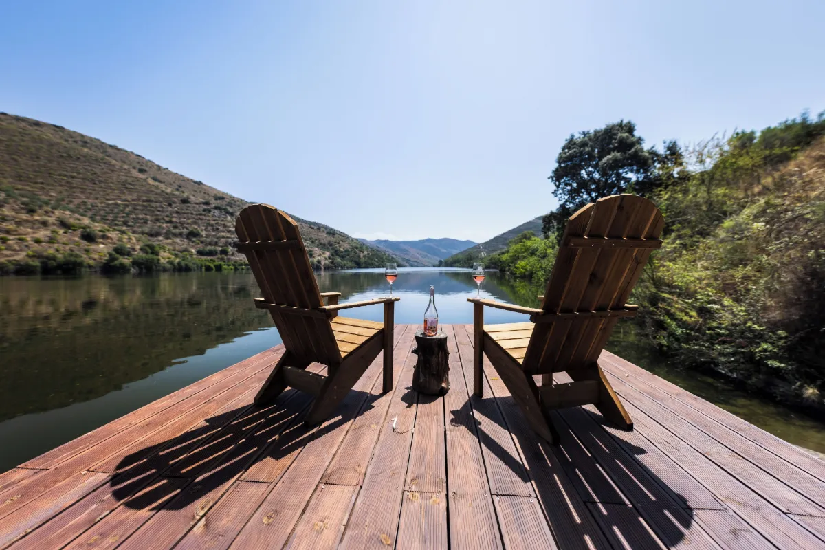 Two wooden lounge chairs on a deck facing the Douro River at Casa do Rio