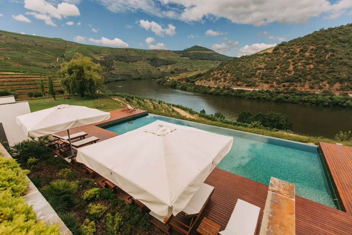 Infinity pool with white parasols above a bend of the Douro River at Ventozelo Hotel and Quinta
