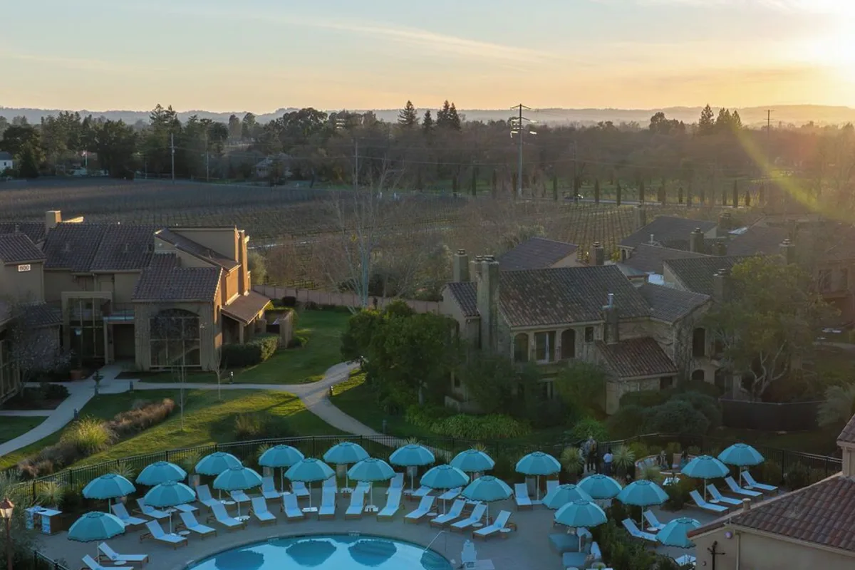 Vinarosa Resort & Spa near Santa Rosa at sunset: the pool and its blue umbrellas among the resort buildings, with vineyards beyond