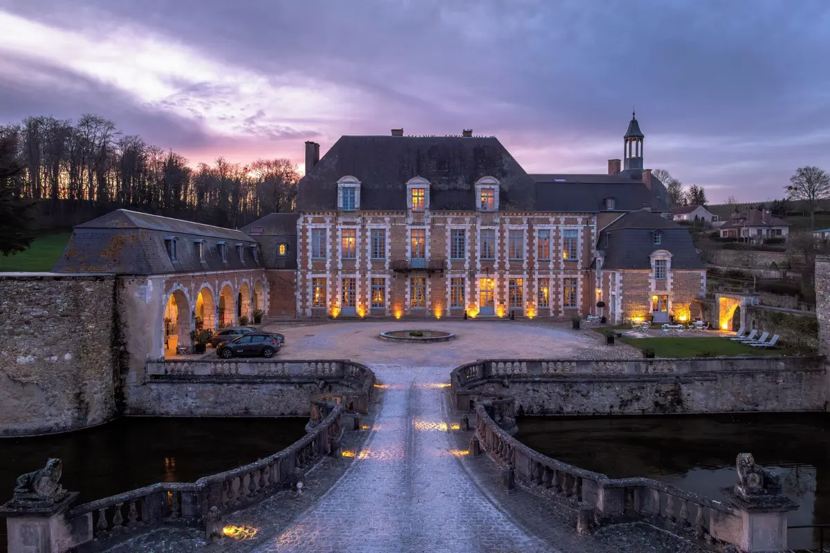 Château d’Étoges at dusk, lit up behind its moat and stone bridge