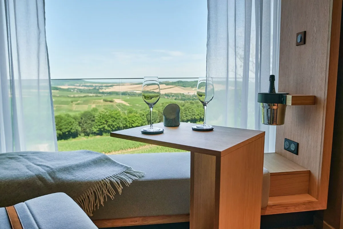 Room window at the Loisium in Mutigny, with two glasses and Champagne vineyards rolling to the horizon