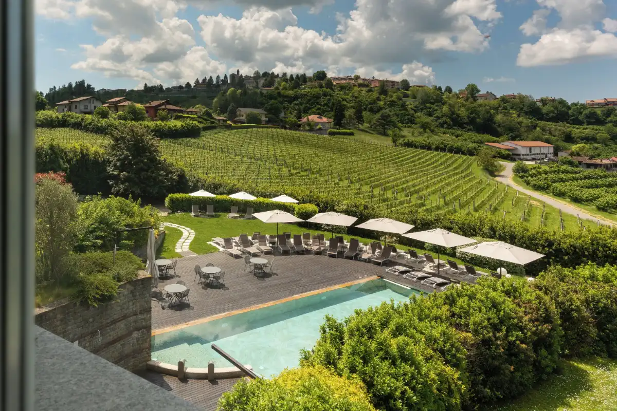 Outdoor pool with loungers and umbrellas at Relais Villa d'Amelia, surrounded by vineyard rows